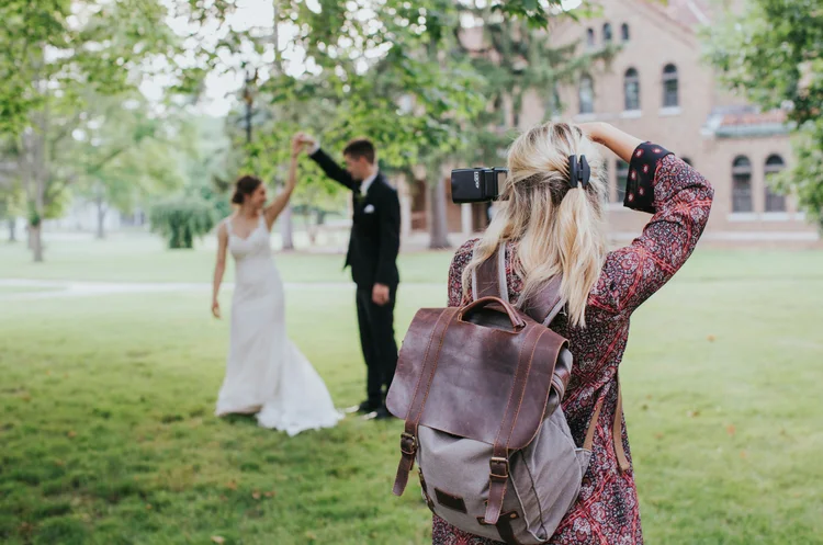 Photographer taking pictures of bride and groom dancing outdoors