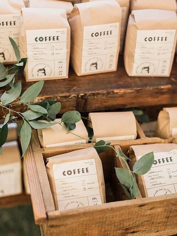 Custom coffee bag wedding favors displayed in rustic wooden crates with greenery