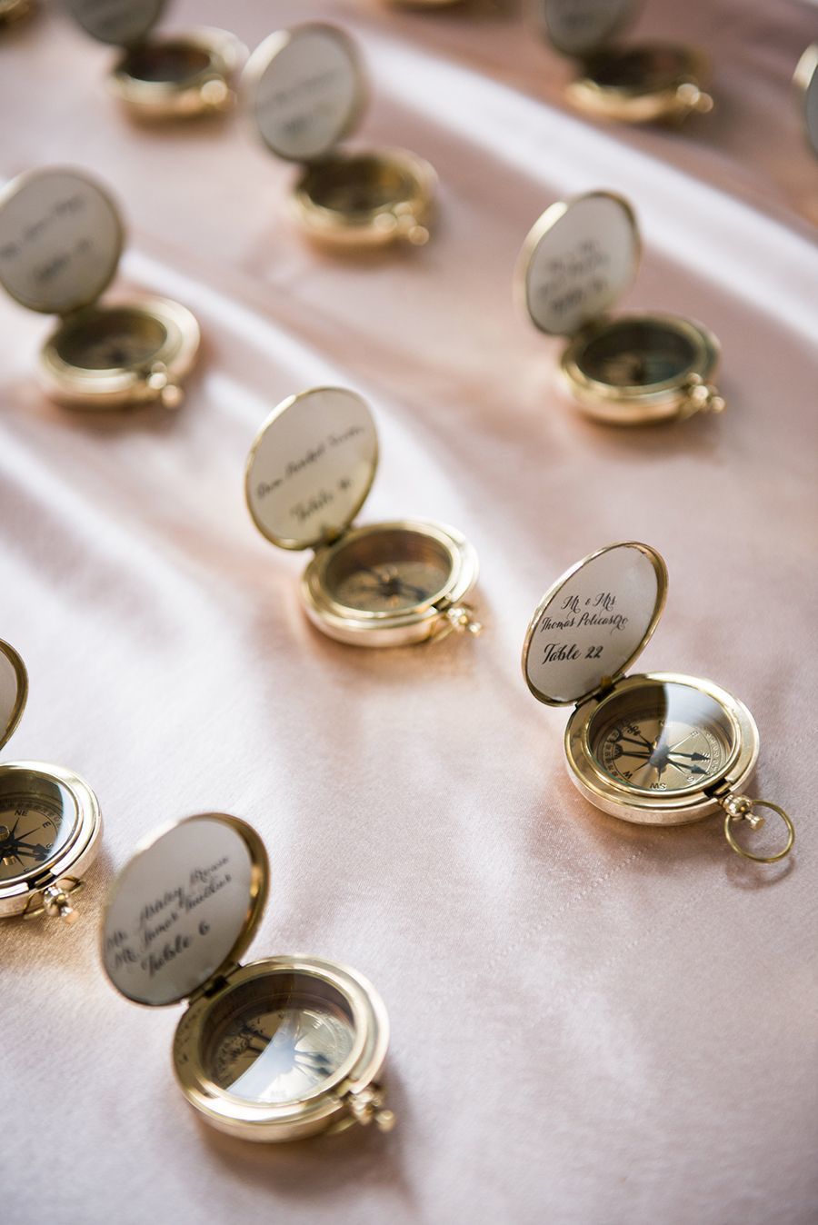 Gold compass wedding favors with calligraphy escort cards inside