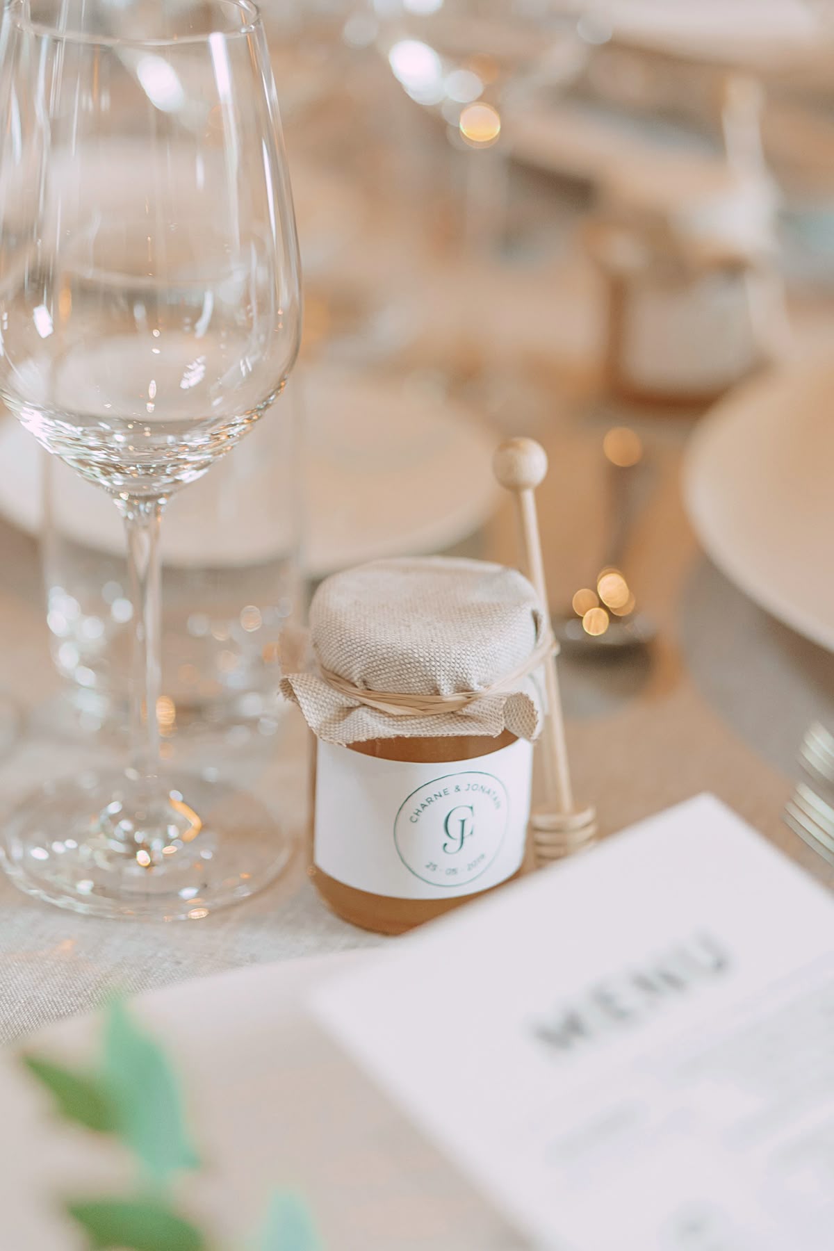 Mini honey jar wedding favor with linen cover and honey dipper at place setting