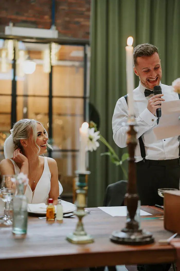 Groom laughing while reading mr and mrs quiz questions at wedding reception