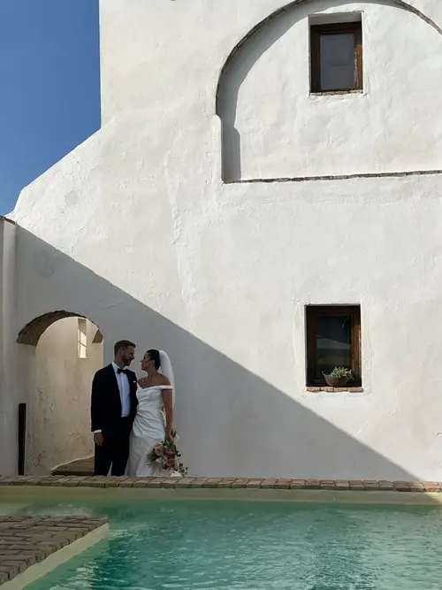 Bride and groom by poolside building
