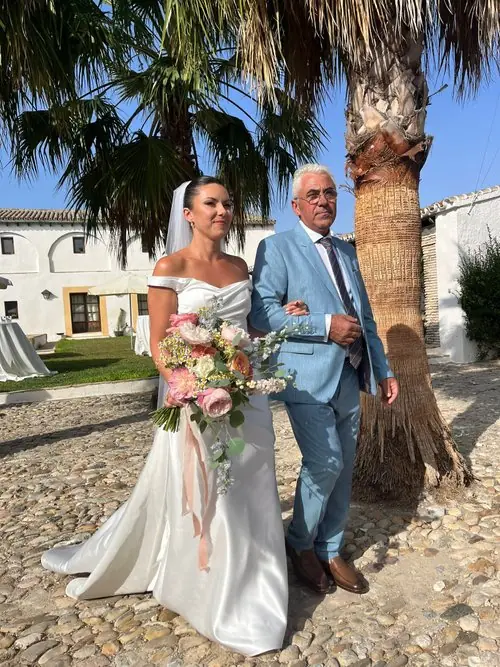 Bride with father under ceremony arch